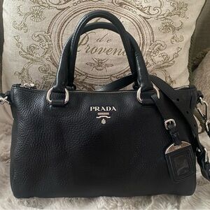 Prada Black Textured Leather satchel with top handles and shoulder strap.